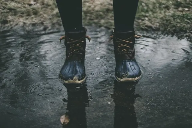 Person standing in puddle with boots