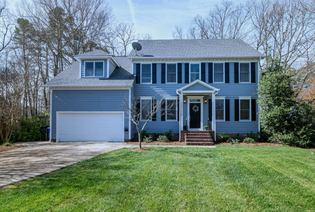 Blue house with green lawn and trees.